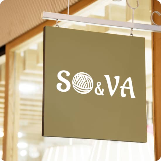 Квадратна вивіска золотого кольору з білим логотипом SO&VA підвішана на металевій трубі на фоні великої скляної вітрини. В логотипі буква О зроблена у вигляді клубка ниток